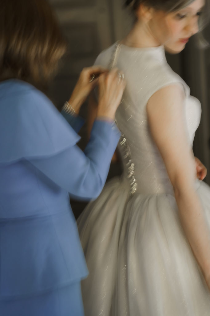 mom in blue dress helps bride with grace kelly inspired gown