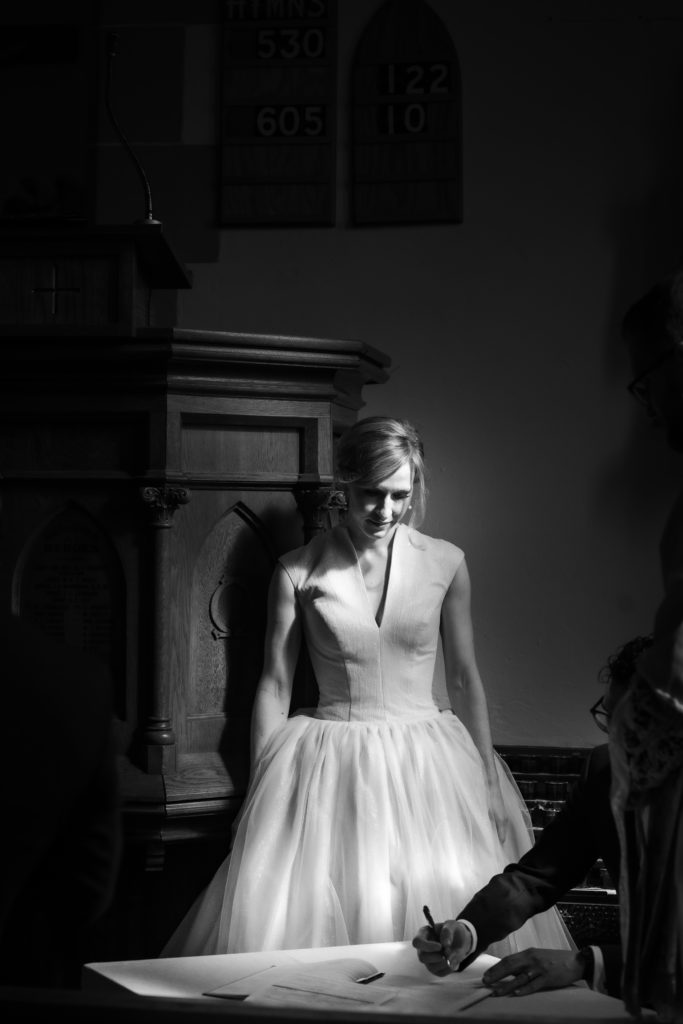 bride groom standing in harsh light signing registry