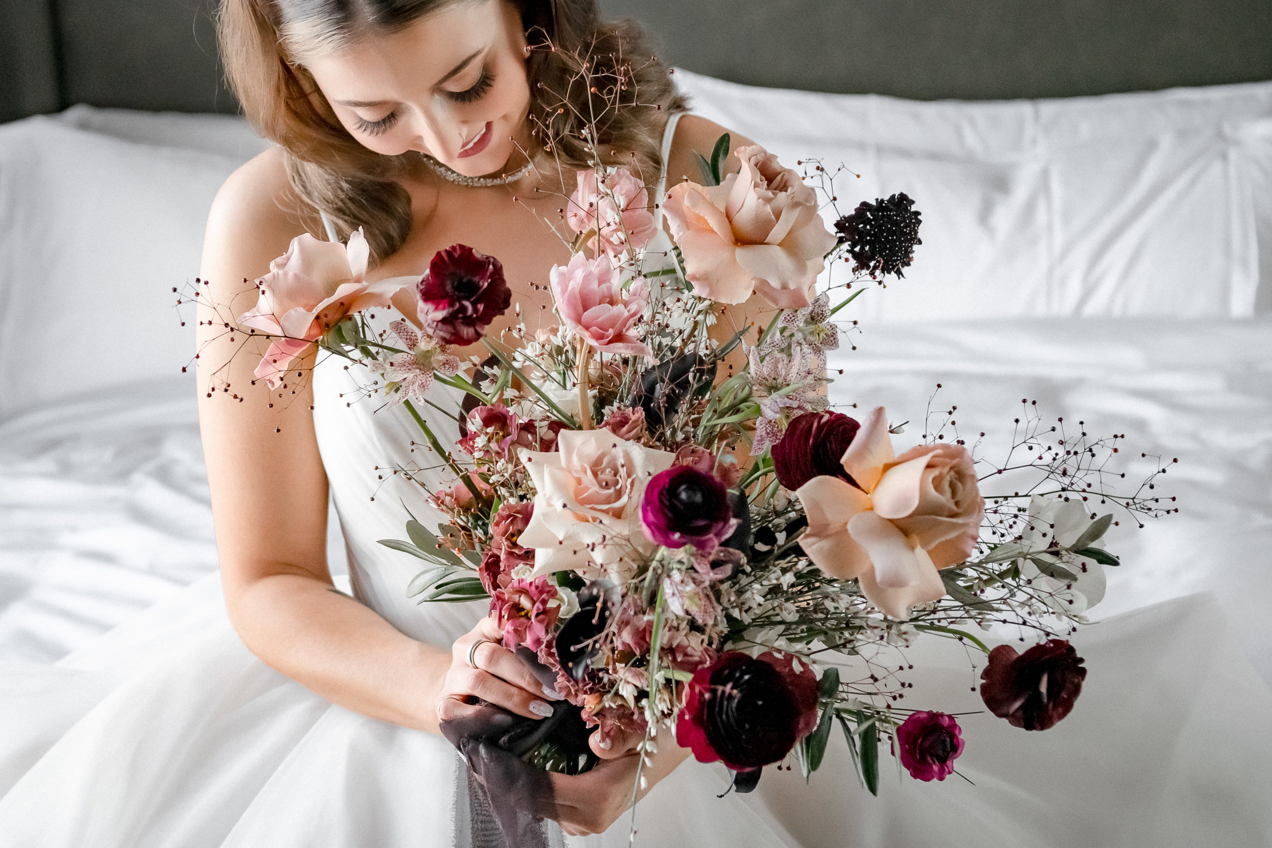bride holding bouquet of flowers with pink tones