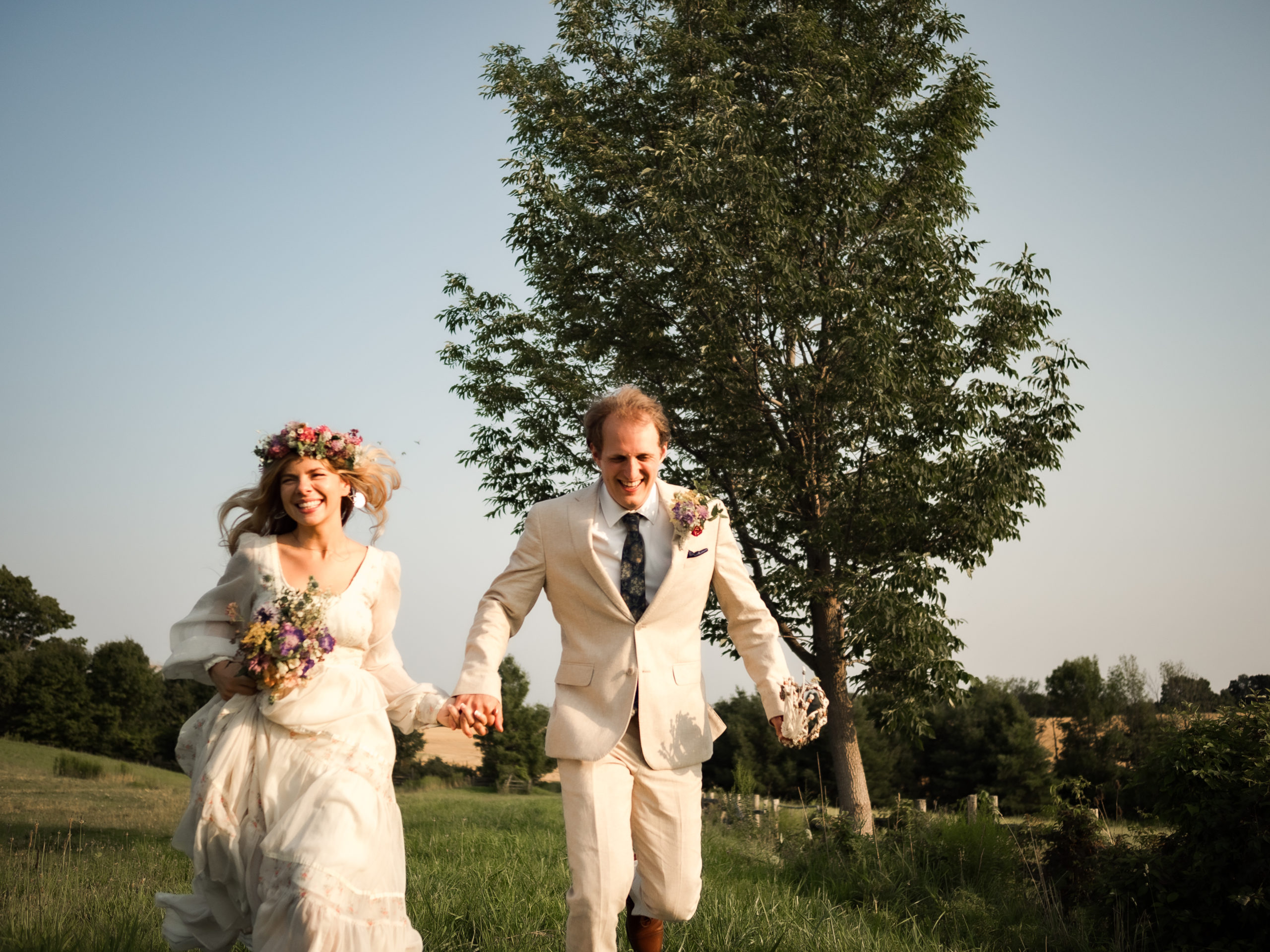 boho bride groom running in field at sunset