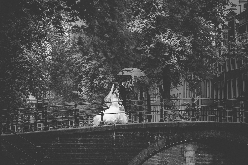 bride groom walking over bridge in Amsterdam