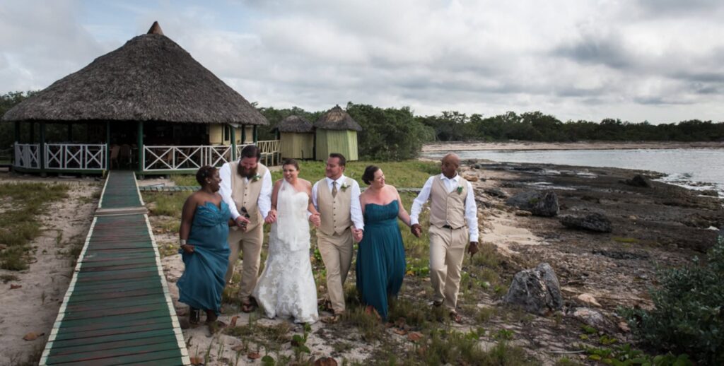 wedding party in teal dresses walking on beach in Cuba