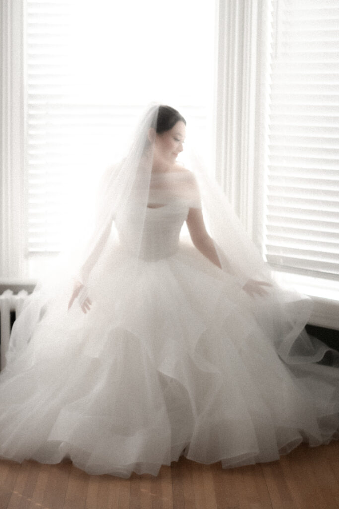 bride in ball gown sitting on window sill