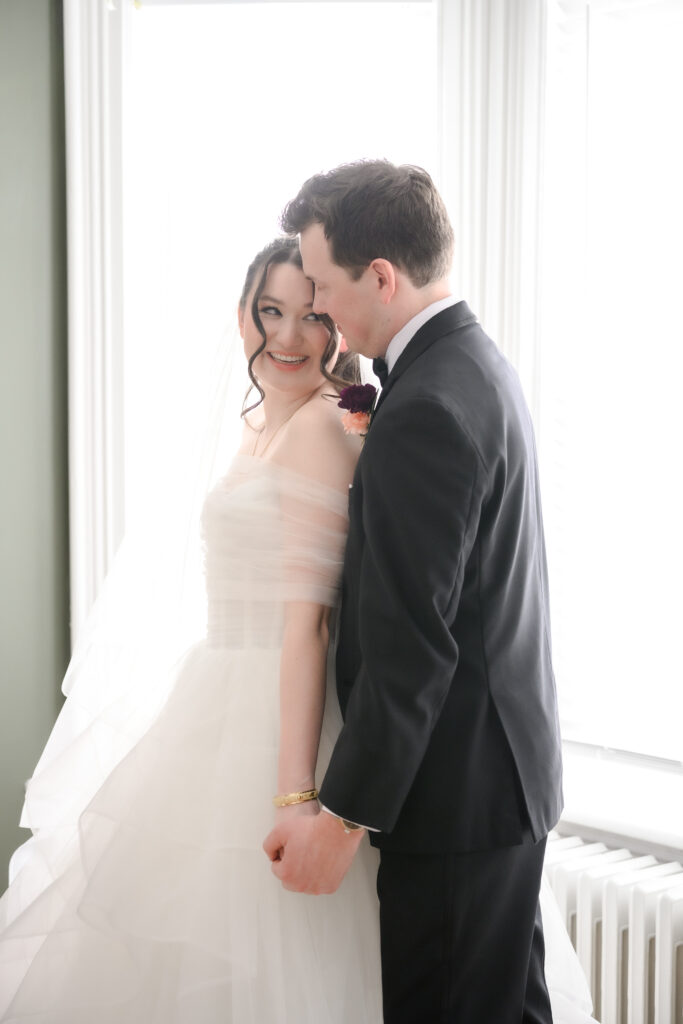 bride looking back at groom in front of book shelve